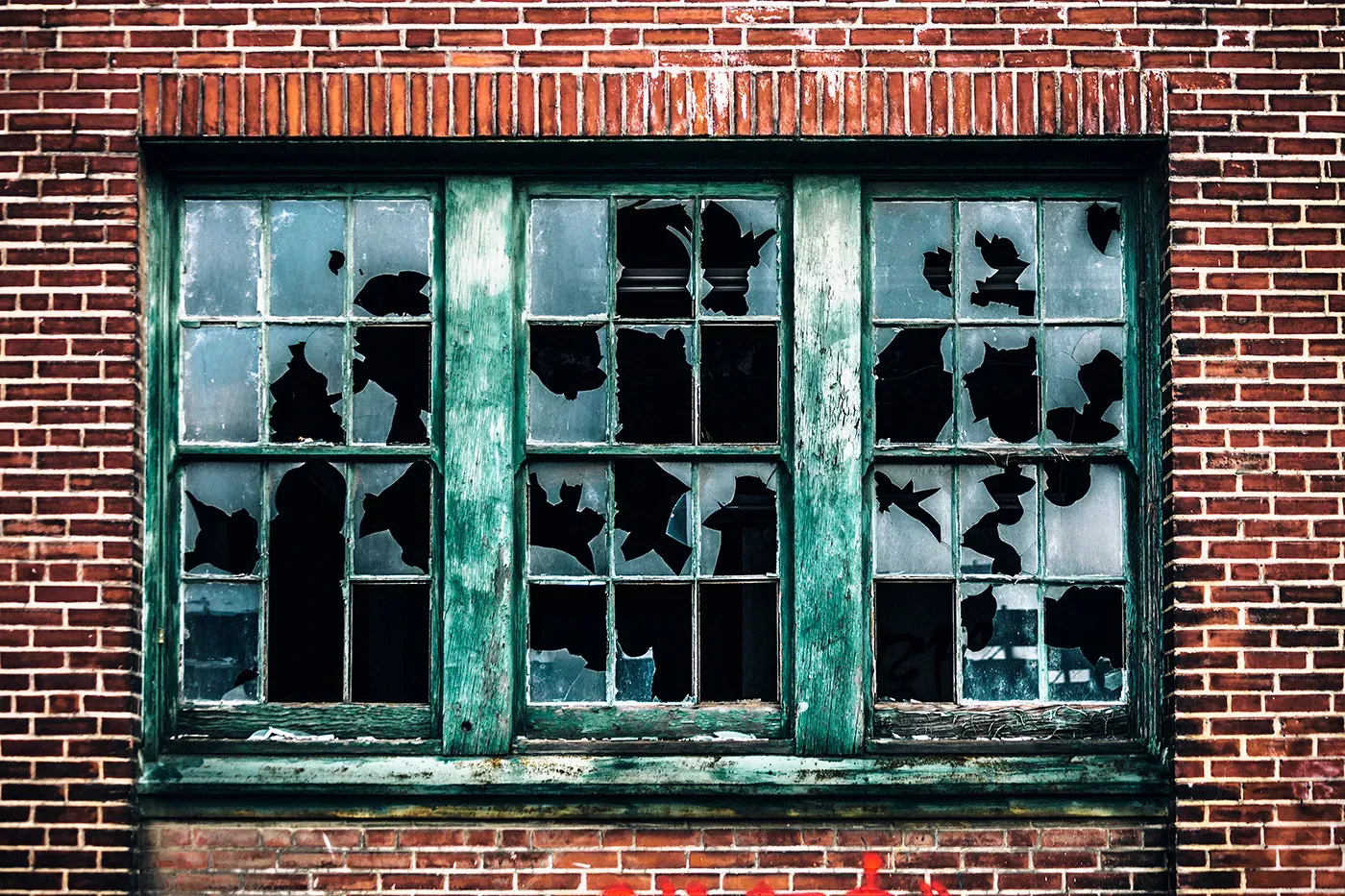 A brick building facade whose windows have all been smashed one after another, illustrating the Broken Windows Effect.